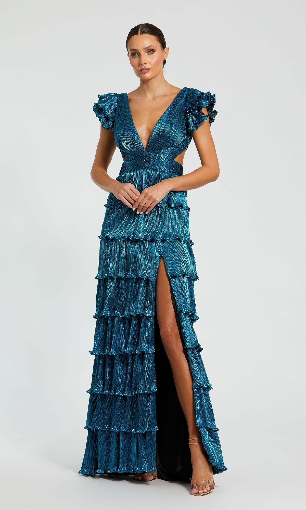 A woman poses against a plain light background in the Mac Duggal Open-Back Tiered Formal Dress 26740, featuring a teal hue, flutter sleeves, deep V-neckline, lace-up open back, tiered ruffles, and a high slit.